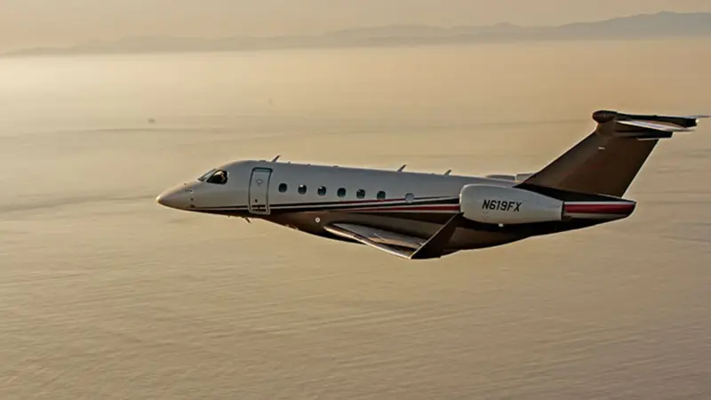 A private jet with registration N619FX flying over water at sunset.