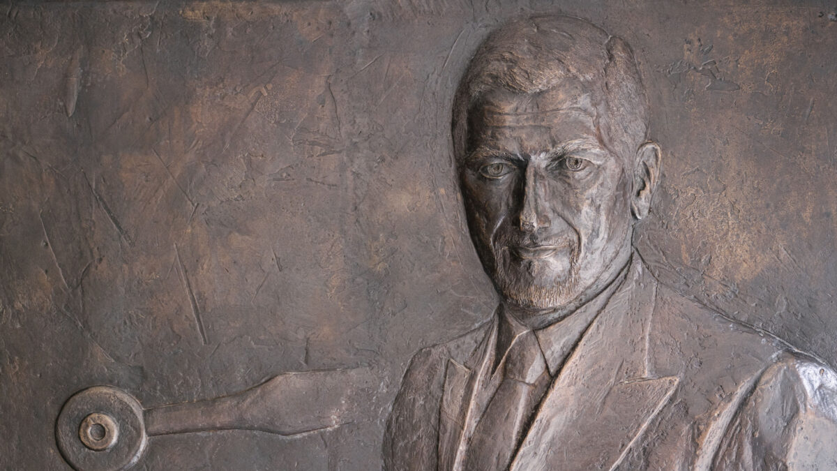 Bronze relief plaque depicting a man's portrait in a suit and tie.