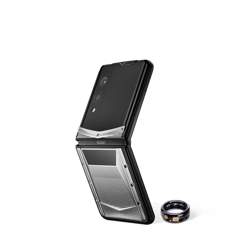 A Vertu folding phone standing upright next to a small smart ring on a white background.