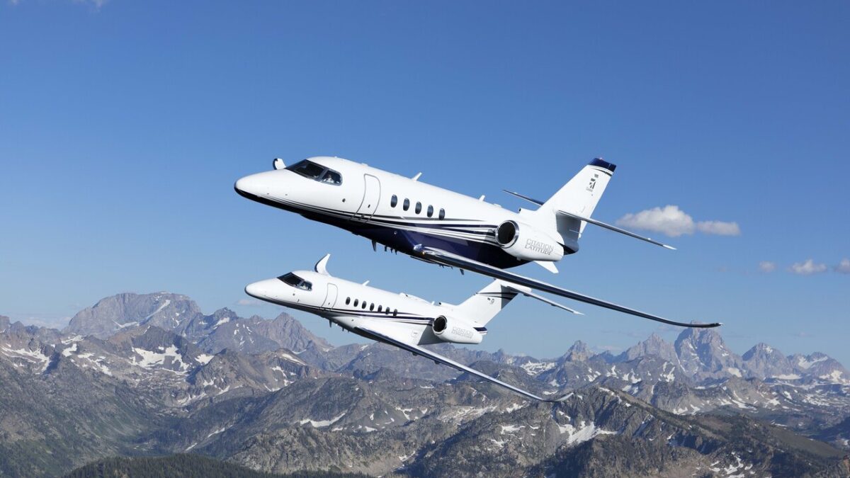 Two Cessna Citation business jets flying in formation above snow-capped mountains.