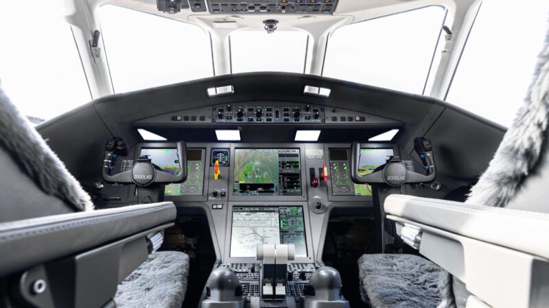 Cockpit interior of a Dassault Falcon 2000 jet showing avionics displays and control yokes labeled 2000LXS.