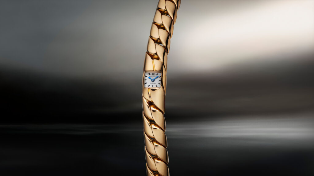 Close-up of a gold twisted chain-link bracelet watch with a small square white dial reading Jaeger-LeCoultre.