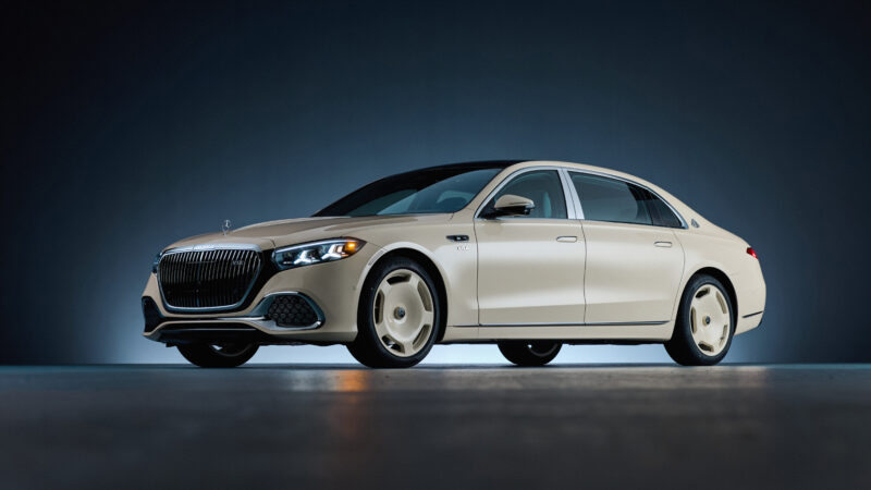 A cream-colored Mercedes-Maybach S 680 sedan photographed in a studio against a dark blue background.