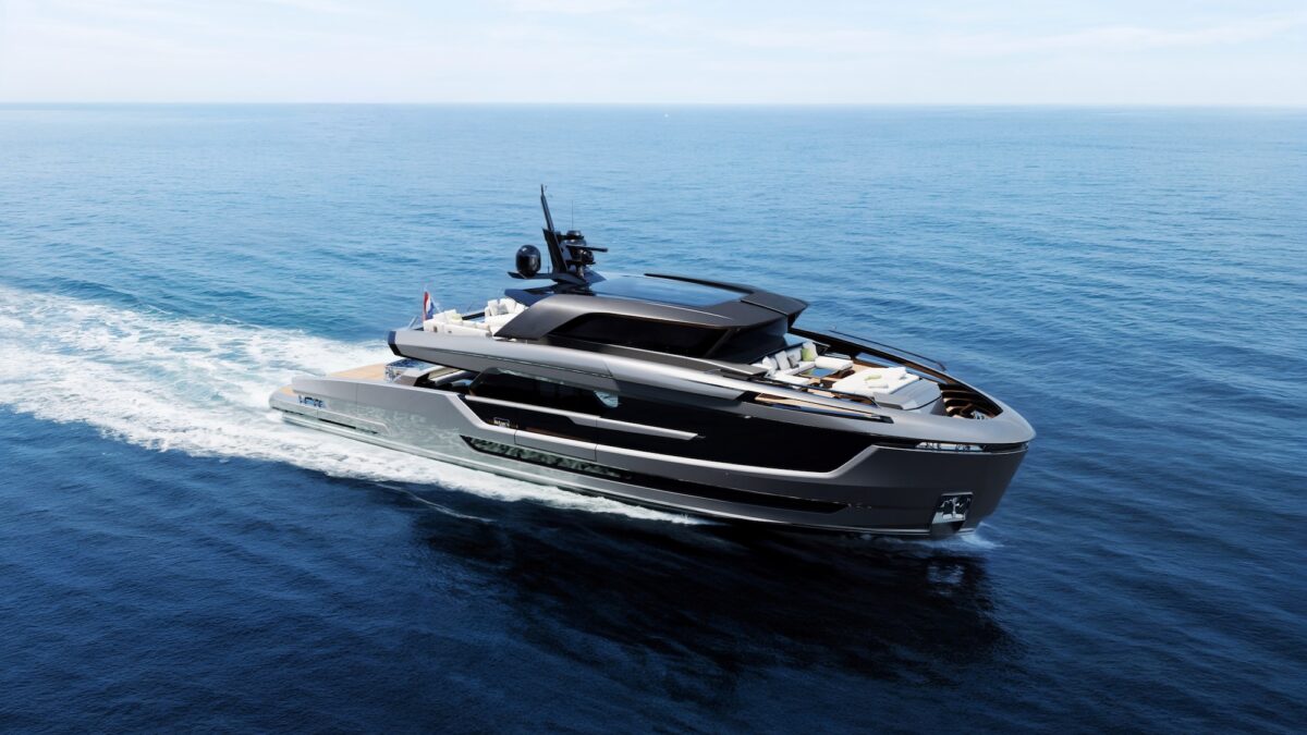 A sleek dark motor yacht cruises across open blue water, seen from above.