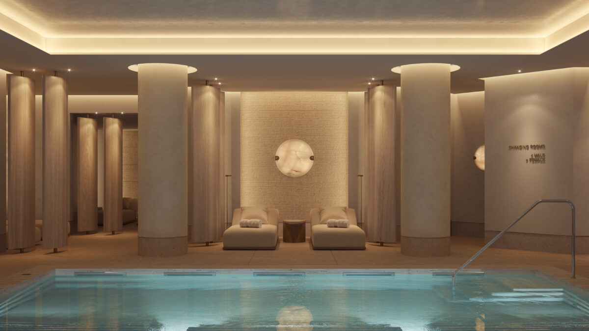 Interior of a luxury hotel spa with a pool, loungers, columns, and a changing rooms sign.