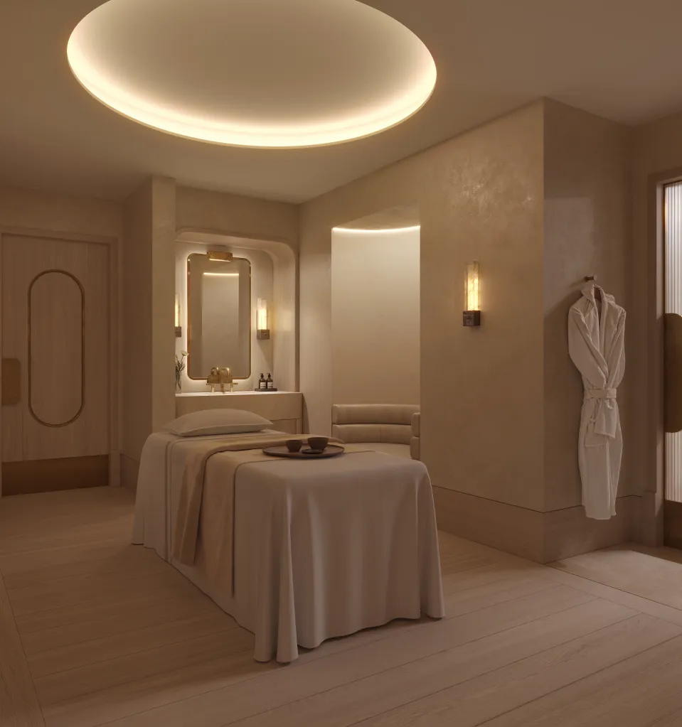 A minimalist spa treatment room with a massage table, soft circular ceiling light, and a white robe hanging on the wall.
